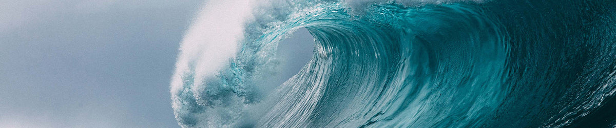A dramatic curling ocean wave with turquoise blue water and white foam, photographed from within the wave tunnel.