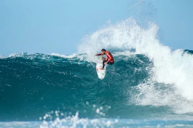 Surfer riding a wave in the ocean with clear blue sky